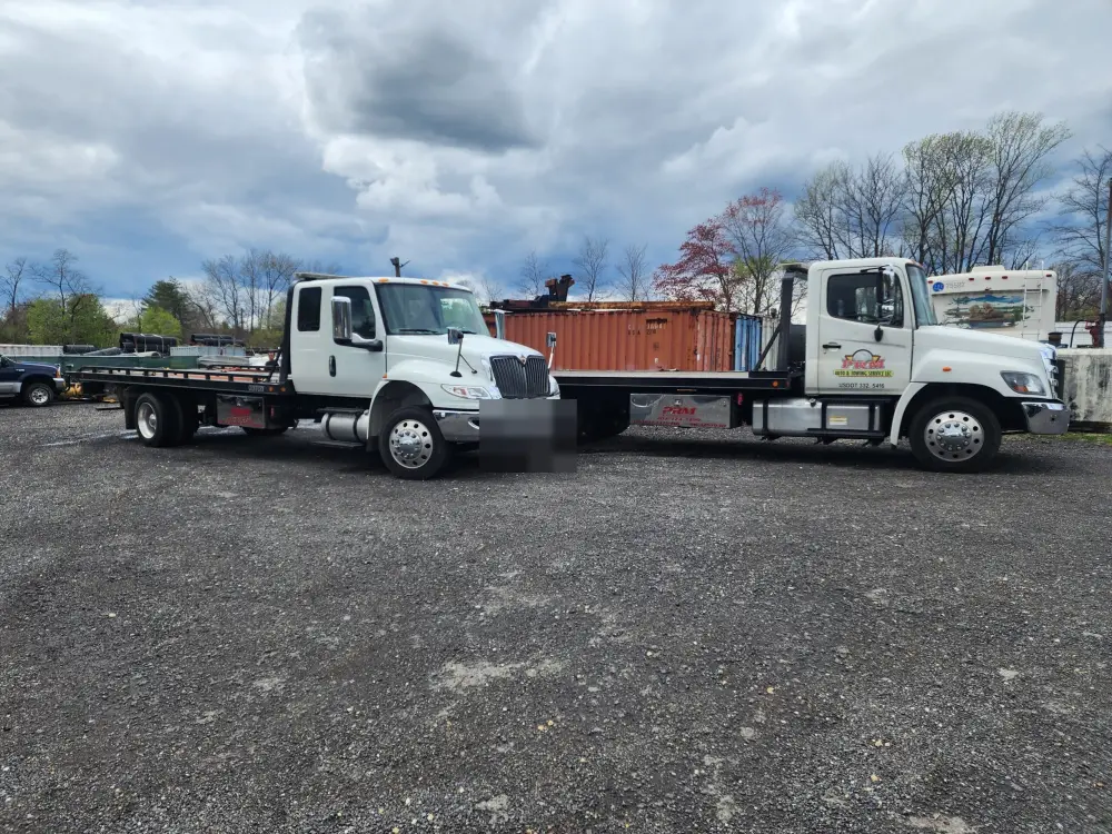 Two white PRM Auto and Towing flatbed carriers parked side by side at the company yard.